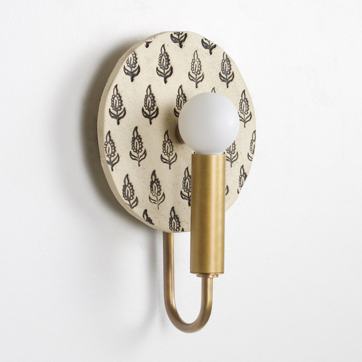 Edith ADA Sconce shown in Heirloom Brass with a Black and Cream Floral Ceramic Canopy