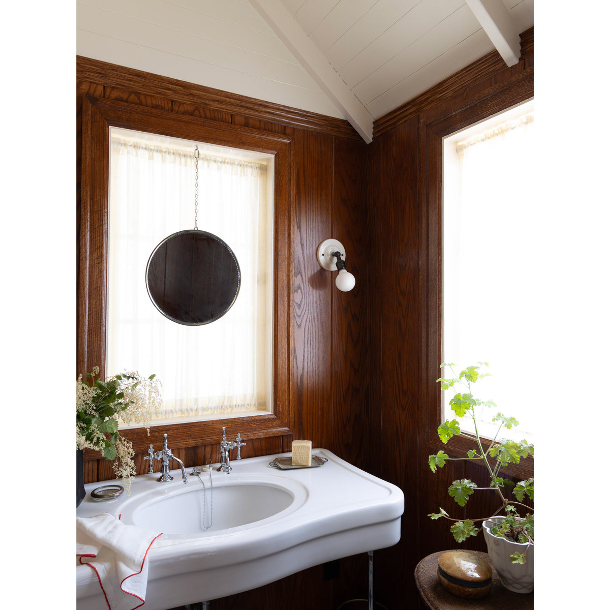 Grace Flush Sconce shown in Graphite Patina with a Gloss White Ceramic canopy and no shade and a Tala Bulb. Interior design by Sarah J. Meyer Design